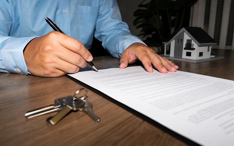Firma de un contrato de compraventa con las llaves sobre la mesa