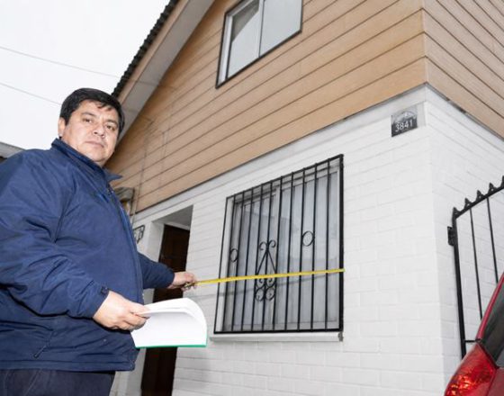 Un tasador toma medidas en el exterior de una casa